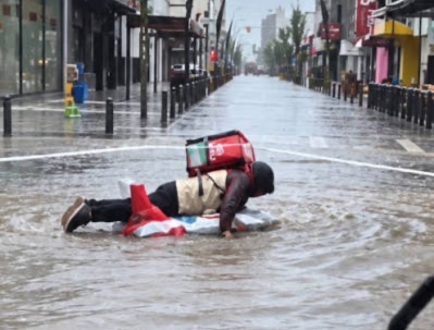 Tandil | En plena inundación, un repartidor siguió trabajando sobre una tabla.-
